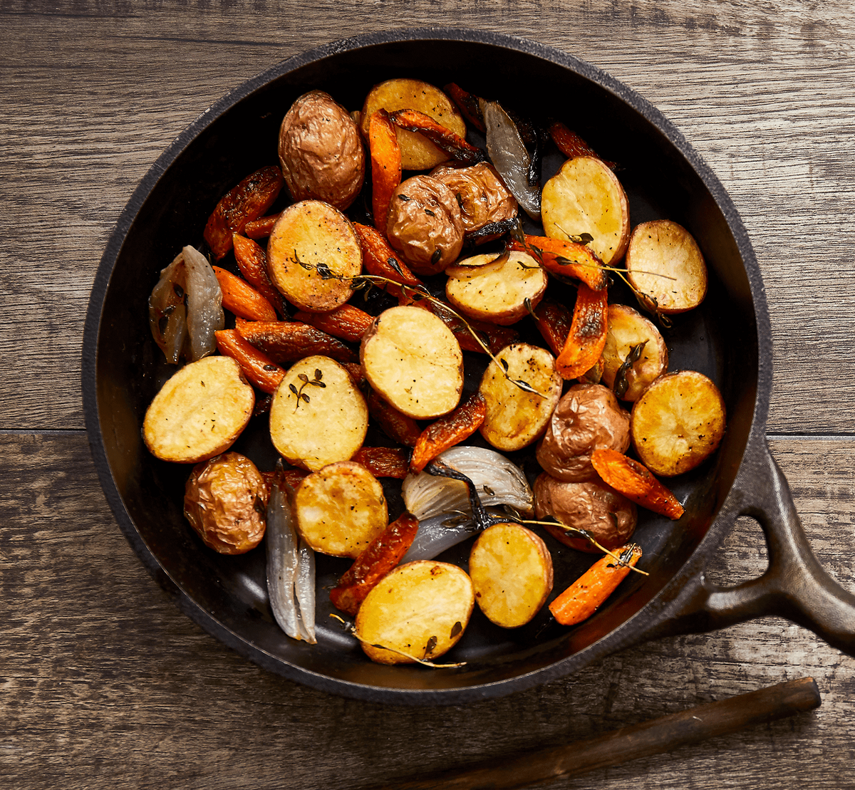 Fried vegetables in a cast iron skillet on a wooden surface