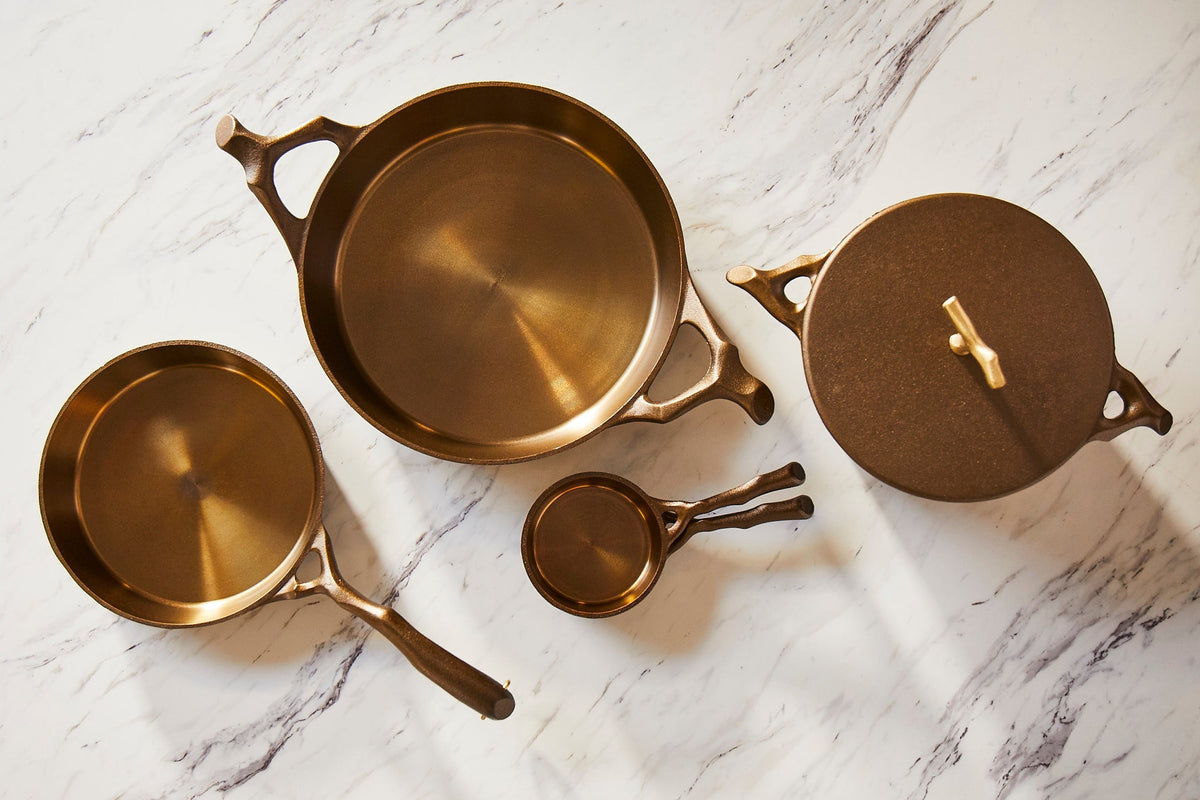 Set of brass cast iron including pots and lids on a marble surface